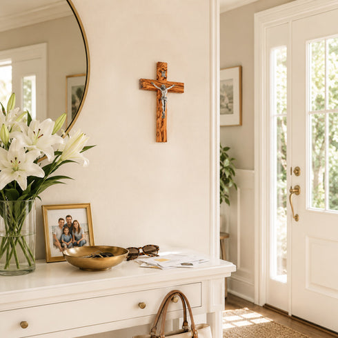 Decorative entryway with a crucifix, flowers, and framed photos on a white console table.