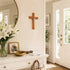 Decorative entryway with a crucifix, flowers, and framed photos on a white console table.