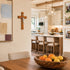 Modern kitchen with wooden dining table, fruit bowl, and cross on wall.