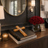 Decorative setup with books, cross, and vase of red roses on a wooden surface.