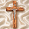 Wooden cross with silver Jesus figure on a textured beige background