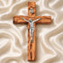 Wooden cross with silver Jesus figure on a textured beige background