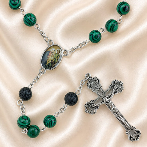 A rosary with green marbled beads, black lava stone beads, a silver crucifix, and an oval centerpiece medal.