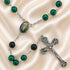 A rosary with green marbled beads, black lava stone beads, a silver crucifix, and an oval centerpiece medal.