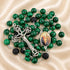 A green and black malachite rosary with a crucifix,and a medallion containing a religious image.