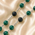 A beaded necklace with green malachite beads with black lava stone beads, on a beige satin fabric background.