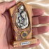 Hand holding a Holy Family olive wood plaque, showing its compact size and natural wood grain