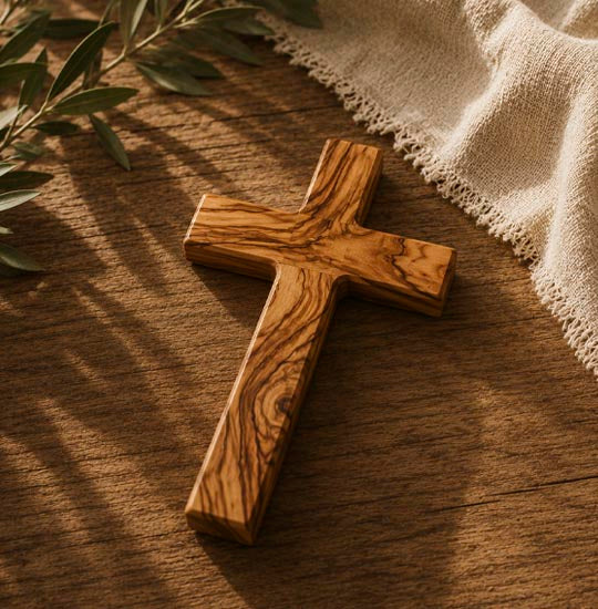 Olive wood cross on a wooden table with olive branch next to it