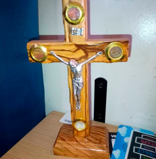 Olive wood cross with Four Elements, silver corpus and INRI plaque, standing on a table.