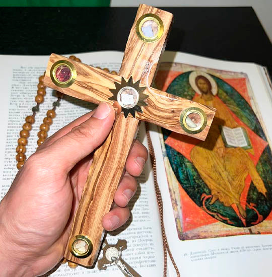Hand-held olive wood Latin cross with Four Elements and Star of Bethlehem, over a Bible and a Rosary.