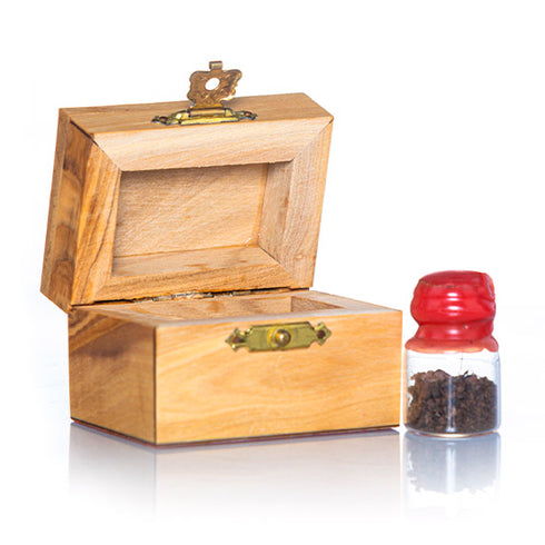 A small handcrafted olive wood box against white background, accompanied by a glass vial with red cap next to it, containing holy soil from the Holy Land.