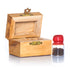 A small handcrafted olive wood box against white background, accompanied by a glass vial with red cap next to it, containing holy soil from the Holy Land.