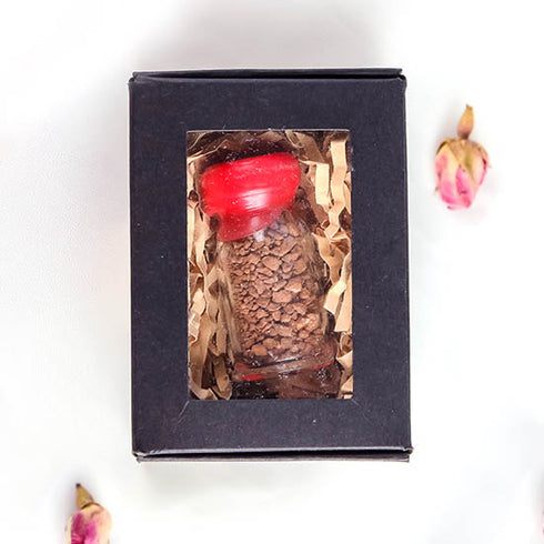 Product image of a Holy Soil vial from the Holy Land with a red cap, elegantly presented in a black box.
