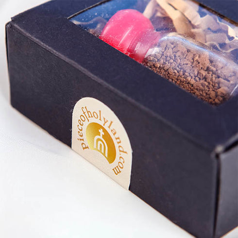 Product image of a Holy Soil vial from the Holy Land with a red cap, elegantly presented in a black box with Piece of Holy Land.