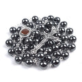 Black hematite rosary with Holy Soil centrepiece and a crucifix on a white background.