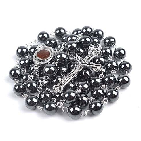 Black hematite rosary with Holy Soil centrepiece and a crucifix on a white background.