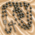 A rosary with dark gray beads, a round medallion and a crucifix, on a beige satin fabric background.