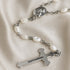 White pearl rosary with silver chain links, oval medallion, and metal crucifix