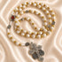 White rosary with Holy Soil centerpiece, Jerusalem cross medals, and silver crucifix on a satin fabric background