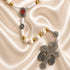 White rosary with Holy Soil centerpiece, devotional medals, and silver crucifix on a satin fabric background