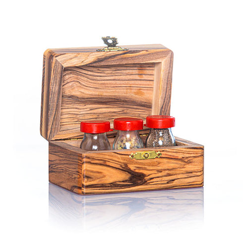 A handcrafted olive wood box against white background, with three glass vials with red caps on it, containing holy water, incense, and holy soil.