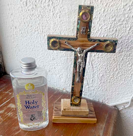 Plastic bottle of the Holy Water from Mary's Well and an olive wood crucifix next to it.