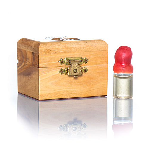 A small handcrafted olive wood box against white background, accompanied by a glass vial with red cap next to it, containing Jordan river holy water.