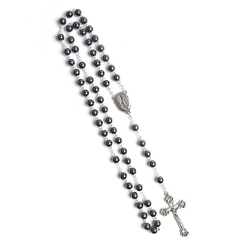 Black hematite stone rosary with a crucifix and Lourdes medal on a white background