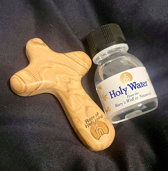 Plastic bottle of the Holy Water from Mary's Well and an olive wood Comfort Cross next to it.