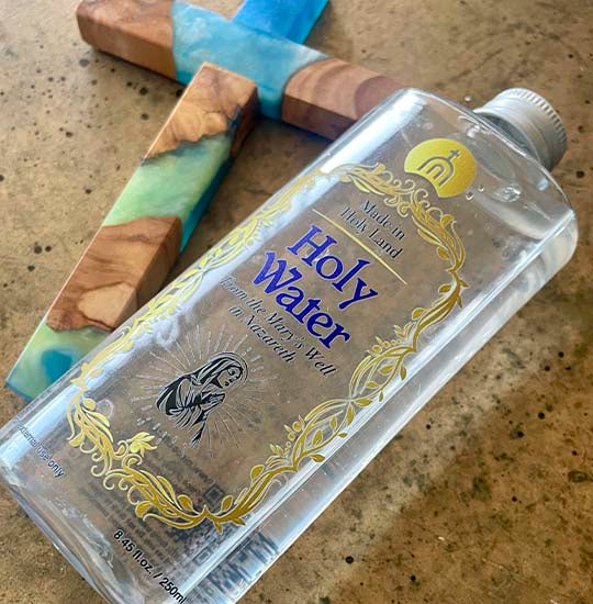 Plastic bottle of the Holy Water from Mary's Well and an olive wood cross next to it.
