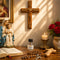 An altar with a wooden cross, a Virgin Mary and baby Jesus statue, rosary, a Holy Water bottle, a Bible, a lit candle, and red roses