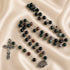 A beaded rosary with green, purple, and brown stone beads connected by silver-tone chains.