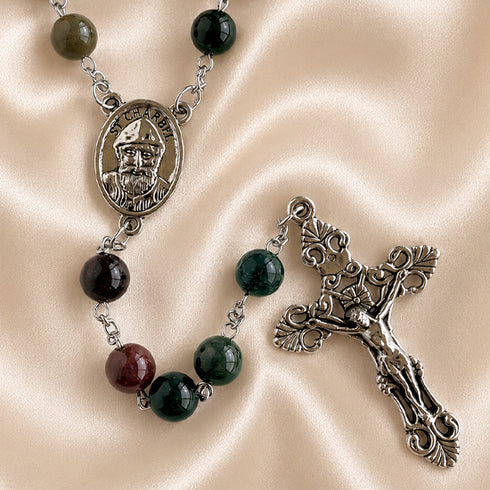 A rosary with dark green, black, and burgundy beads, featuring a silver-toned medallion of Saint Charbel and an ornate crucifix.
