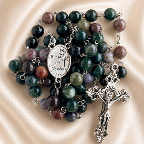 A multicolor gemstone rosary with beads in shades of green, purple, brown, and gray, a silver-tone crucifix and a medallion.