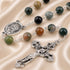 A rosary with beads in green, black, brown, and gray, silver-tone chain links, an oval Saint Charbel medal, and an ornate crucifix.