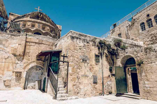 The Church of the Holy Sepulchre rooftop featuring a blue dome, golden iron cross and the Coptic Patriarchate entrance.