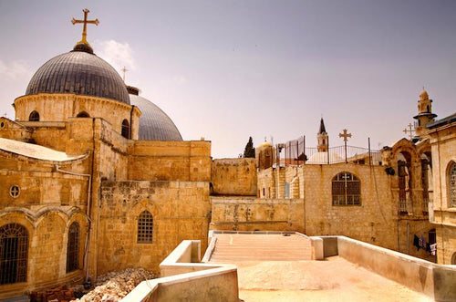 Horizontal view of the Church of the Holy Sepulchre rooftop with its blue dome and golden cross.