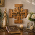 Religious decor with cross, statue, Bible, and flowers on a table.