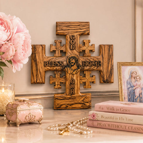 Wooden cross with religious text, books, and flowers on a table.