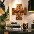 Decorative setup with a wooden cross, books, and a candle on a reflective surface.