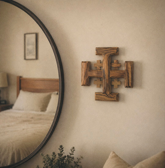 Wooden cross wall art and round mirror in a bedroom setting