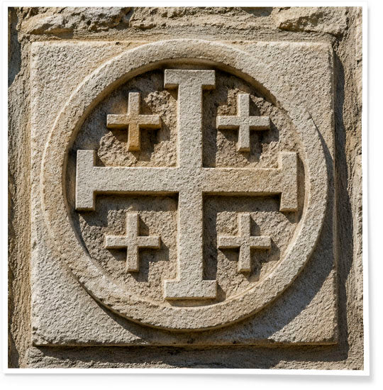 Stone carving of a cross with four additional crosses in a circular design on a stone surface.