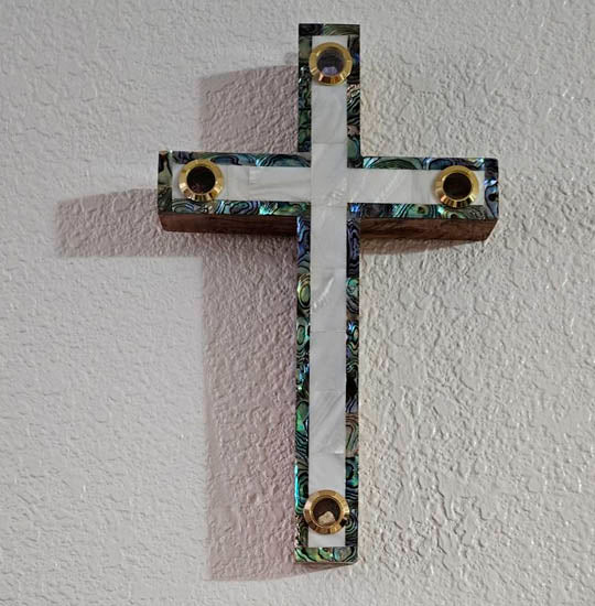 Olive wood Latin cross with white and green Mother of Pearl and Four Elements, hanging on a wall.