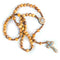 Pack-shot of a handmade olive wood rosary with holy soil, "God Bless Our Home writing featuring a an iron crucifix on a rope.