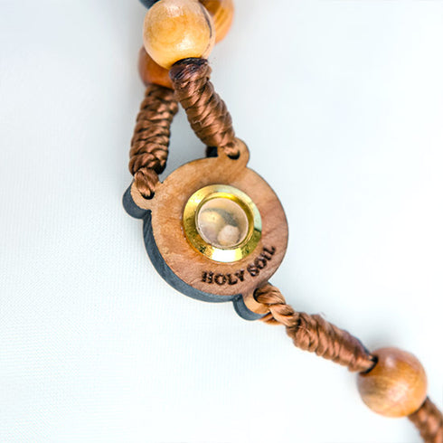 Close up of a centrepiece of an olive wood rosary with embedded Jerusalem stone, laid out on a clean white surface.