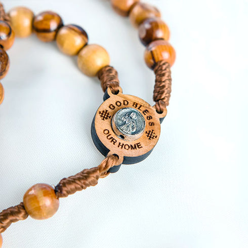 Close up of an handcrafted olive wood rosary featuring an embedded Jerusalem stone, laid out on a clean white surface.