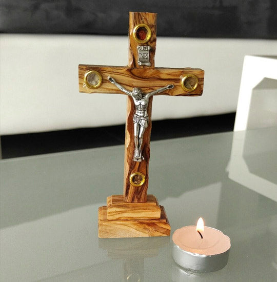 Olive Wood Thorn Cross with Four Holy Elements standing next to a lit candle.