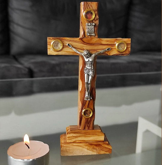 Olive Wood Thorn Cross with Four Holy Elements standing next to a candle.