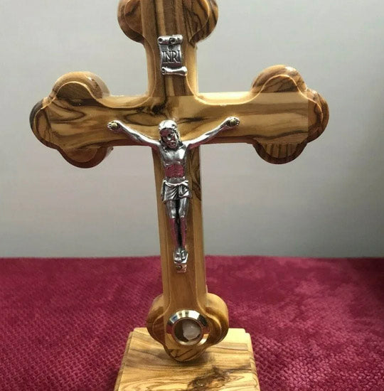 Olive Wood Budded Crucifix standing on a white cloth in a living room.