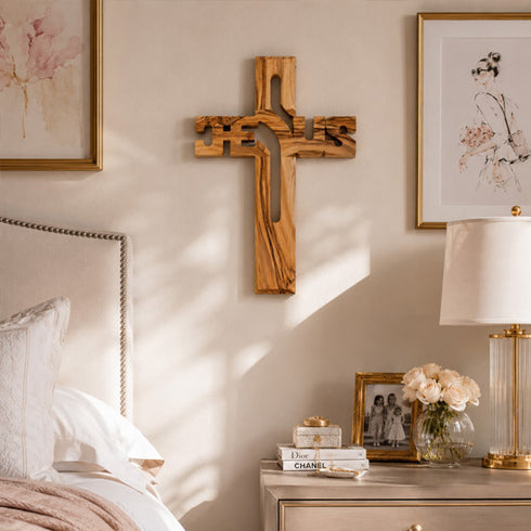 Wooden cross on a wall above a dresser with decorative items in a bedroom setting.